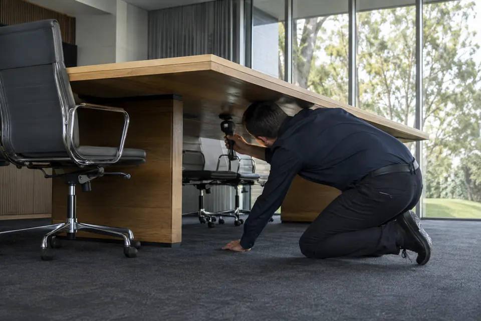 Technician examining beneath a boardroom table
